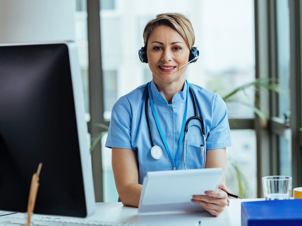 Smiling healthcare professional with headset working call center Smiling female doctor wearing headset while working at medical call center and looking at camera.