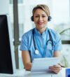 Smiling female doctor wearing headset while working at medical call center and looking at camera.