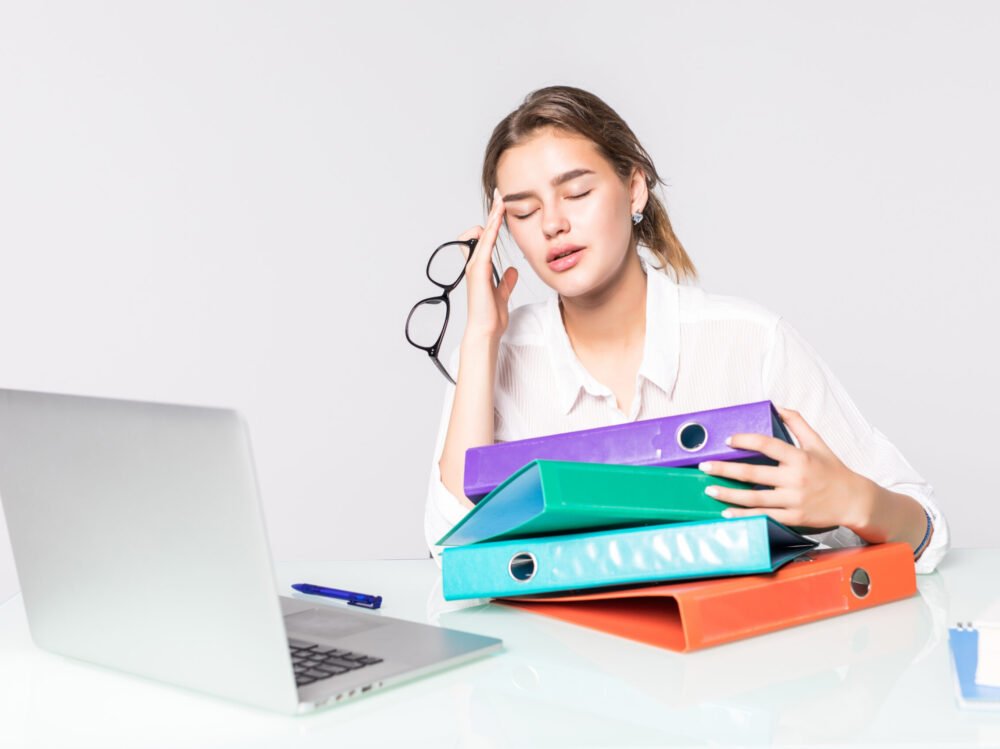 Young tired business woman with folders on office desk isolated on white background Young tired business woman with folders on office desk on white background